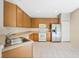 Well-lit kitchen featuring wood cabinetry, white appliances, and tile flooring at 2933 Star Grass Pt, Oviedo, FL 32766