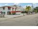Street view of a building with awnings and outdoor patio seating; sign reads, 