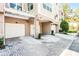 View of multiple unit garages with paved driveway and mature landscaping at 3384 Corona Village Way # 202, Orlando, FL 32835