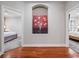Hallway with hardwood floors and an alcove with a colorful painting between two doorways leading to bedrooms at 3400 Park Grove Ct, Longwood, FL 32779