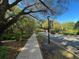 Sidewalk view along a quiet street with mature trees, streetlights and attractive community signage at 437 Wilmington Cir, Oviedo, FL 32765