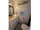 Bathroom featuring a vanity with a granite countertop, a cabinet, toilet, and wood-look flooring at 4798 Windwood Dr, Kissimmee, FL 34746