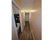 Hallway with wood-look flooring, neutral walls, and a view of a bathroom and white doors at 4798 Windwood Dr, Kissimmee, FL 34746
