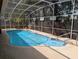 A kidney-shaped pool is surrounded by a screened enclosure and a light-colored concrete deck at 4798 Windwood Dr, Kissimmee, FL 34746