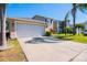 Spacious driveway leading to a two-story home with an attached two-car garage and landscaped yard at 543 Flower Fields Ln, Orlando, FL 32824