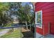 Balcony view of the red house, lush trees, green lawn and charming neighborhood street at 5824 N Dean Rd, Orlando, FL 32817