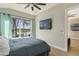 Well lit bedroom with wood-look floors, ceiling fan, large windows and a mounted television at 5824 N Dean Rd, Orlando, FL 32817