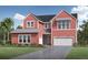 Charming two-story home with a red exterior, two-car garage, landscaped yard, and a paved driveway at 6244 Trailblaze Bnd, St Cloud, FL 34771