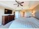 Primary bedroom features a ceiling fan, a dresser with TV, and a view of the bathroom at 7593 Gathering Dr # 203, Reunion, FL 34747