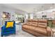 Comfortable living room with a brown leather couch, blue armchairs, and easy access to the patio and kitchen at 7838 Penrose Pl, Wildwood, FL 34785