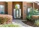 Close-up of a brick home's entrance with a decorative door, lush landscaping, and a charming wind chime at 437 Wilmington Cir, Oviedo, FL 32765
