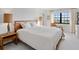 Sunlit bedroom with white walls and carpet and a wooden bed frame and accent furniture at 100 S Interlachen Ave # 503, Winter Park, FL 32789