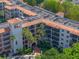 Elegant multi-story building with manicured landscaping, a terracotta tile roof, and tropical palm trees at 100 S Interlachen Ave # 503, Winter Park, FL 32789