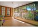 Enclosed sunroom featuring brick floors, multiple screened windows, and a view of lush greenery at 1120 Sheeler Ave, Apopka, FL 32703
