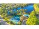 Aerial view of tennis courts and a pool surrounded by lush greenery next to a lake at 122 Spreading Oak Ct, Sanford, FL 32773