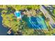 Aerial view of tennis courts and a pool surrounded by lush greenery next to a lake at 122 Spreading Oak Ct, Sanford, FL 32773