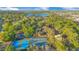 Aerial view of tennis and pickleball courts, lake, and lush greenery under a partly cloudy sky at 122 Spreading Oak Ct, Sanford, FL 32773