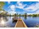 Scenic view of a wooden dock extending into a calm lake surrounded by lush green trees under a blue sky at 122 Spreading Oak Ct, Sanford, FL 32773