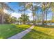 Lush green lawn with a walking path leading to park benches and picnic tables overlooking a tranquil lake under a sunny sky at 122 Spreading Oak Ct, Sanford, FL 32773