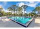 Outdoor swimming pool with clear blue water and lounge chairs beside a lake surrounded by trees under a sunny sky at 122 Spreading Oak Ct, Sanford, FL 32773