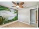 This bedroom features a tropical mural, a modern fan, and light hardwood floors at 1514 Pelican St, Longwood, FL 32750