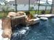 Close-up of the beautiful rock waterfall flowing into the screened-in pool area at 1521 Gants Cir, Kissimmee, FL 34744