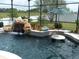 Inground pool featuring a rock waterfall, lush landscaping, and a unique swim-up table with an umbrella at 1521 Gants Cir, Kissimmee, FL 34744