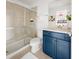 This bathroom has a vanity with blue cabinetry, a sliding glass shower door, and a plush bathmat at 2320 Lelani Cir, Davenport, FL 33897