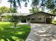 Charming single-story home with a well-manicured lawn, green door, and a spacious carport at 2405 Dellwood Dr, Orlando, FL 32806