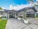View of the home's gray exterior, well-kept landscaping, and a modern, open carport at 2405 Dellwood Dr, Orlando, FL 32806