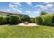 Landscaped backyard with trimmed hedges and a brick fire pit for outdoor relaxation at 2731 Cypress Tree Trl, St Cloud, FL 34772