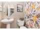 A charming bathroom features a pedestal sink, floral shower curtain, and round mirror at 2731 Cypress Tree Trl, St Cloud, FL 34772