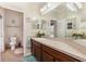 Bright bathroom with cherry cabinets, large mirrors, and decorative floral accents at 2731 Cypress Tree Trl, St Cloud, FL 34772