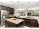 Open-concept kitchen with dark wood cabinetry, granite countertops, stainless appliances, and island with seating at 2731 Cypress Tree Trl, St Cloud, FL 34772