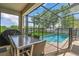 Covered patio with outdoor dining set and a screened-in pool with lake views at 2775 Bookmark Dr, Kissimmee, FL 34746