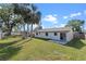 Expansive backyard featuring a concrete patio, lush green lawn, and mature palm trees, perfect for outdoor entertaining at 2955 Foxcroft Ln, South Daytona, FL 32119