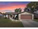 Charming single-story home with a well-manicured lawn, two-car garage, and a brick facade against a sunset sky at 2955 Foxcroft Ln, South Daytona, FL 32119