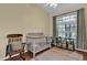 Bright bedroom with natural light, featuring a crib, rocking chair, and a decorative rug at 322 Harbor Trl, Enterprise, FL 32725
