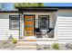 A cozy front porch with a modern orange door, seating, and stylish details enhance this home's entrance at 407 E Jersey St, Orlando, FL 32806
