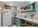 Well-lit kitchen with sage green cabinets, quartz counters, a breakfast bar, and modern appliances at 407 E Jersey St, Orlando, FL 32806