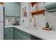Close up of a well-lit kitchen featuring sage green cabinetry, a stainless-steel faucet, and quartz countertops at 407 E Jersey St, Orlando, FL 32806