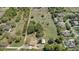 Detailed aerial view focusing on a property with a home, outbuilding, and a large open area, surrounded by trees and other houses at 4550 Chandler Rd, Apopka, FL 32712