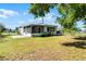 View of the backyard featuring an expansive lawn, a screened-in patio, and mature shade trees at 4751 Deer Run Rd, St Cloud, FL 34772