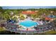 Aerial view of a community pool area with a spacious pool, lounge chairs, and a covered patio near a lake at 4761 Ormond Beach Way, Kissimmee, FL 34746