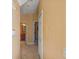 Hallway with tile flooring leading to a bathroom, with linen closet and neutral color palette at 4772 Vero Beach Pl, Kissimmee, FL 34746