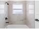 Modern bathroom features tub with shower and striking marble-look tile surround at 4774 Sw 142Nd Place Rd, Ocala, FL 34473