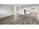 Open-concept living room with modern gray wood floors leading to the bright kitchen and bathroom at 6003 W Harwood Ave, Orlando, FL 32835