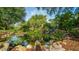 Picturesque view of a tranquil pond with a rock waterfall feature surrounded by lush greenery at 806 Lucaya Loop, Davenport, FL 33897
