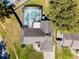 This aerial view shows the home, screened in pool and patio, roof, driveway, and yard at 9501 Holbrook Dr, Orlando, FL 32817