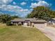 Charming single-story home with a lush green lawn, stone accents, and mature trees under a bright, cloudy sky at 9501 Holbrook Dr, Orlando, FL 32817